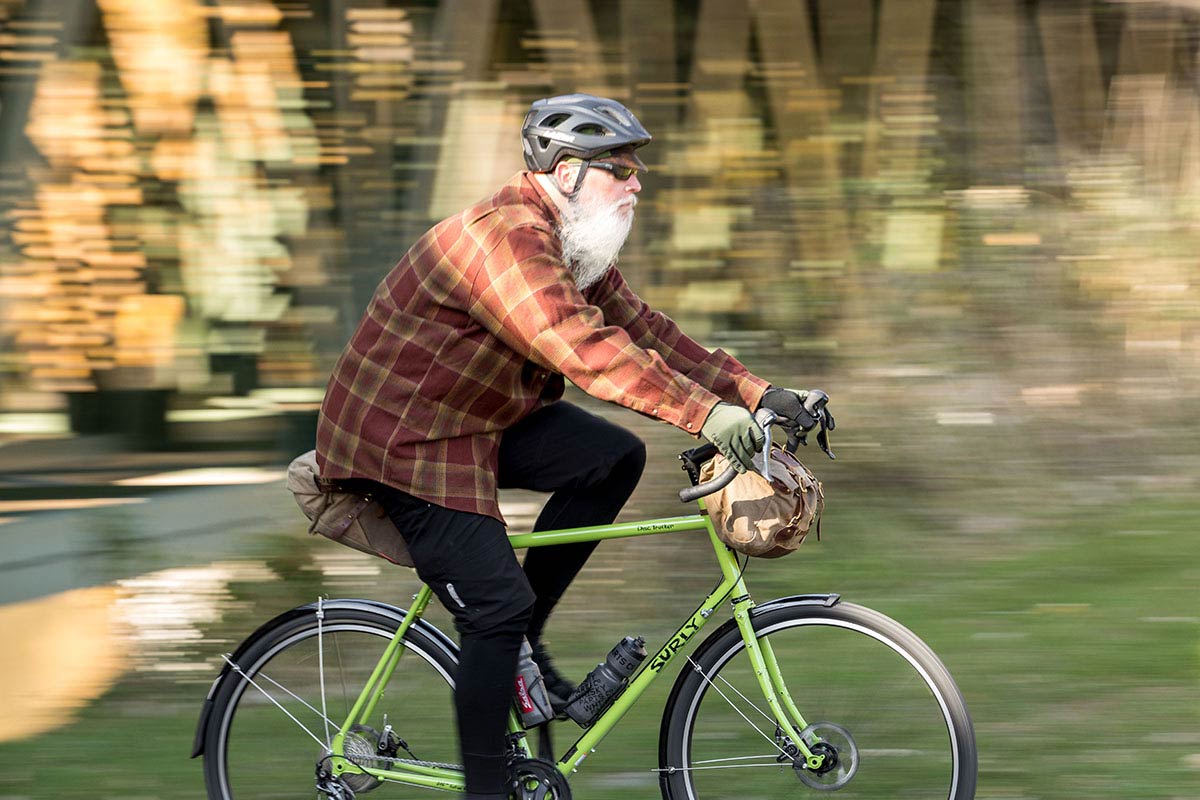 Person in flannel shirt riding Disc Trucker bike with handlebar bag and seat bag