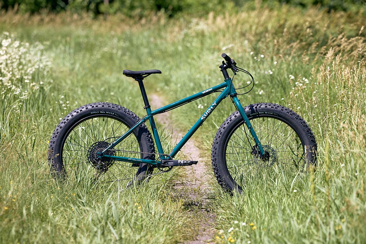 Surly Wednesday fat bike side view, green color on single track in grassy prairie