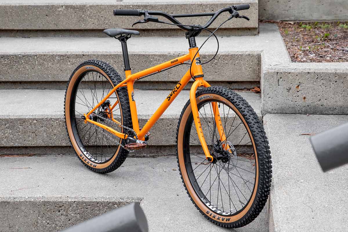 Surly Lowside bike, three-quarter front view, Dream Tangerine color, leaning up against concrete steps