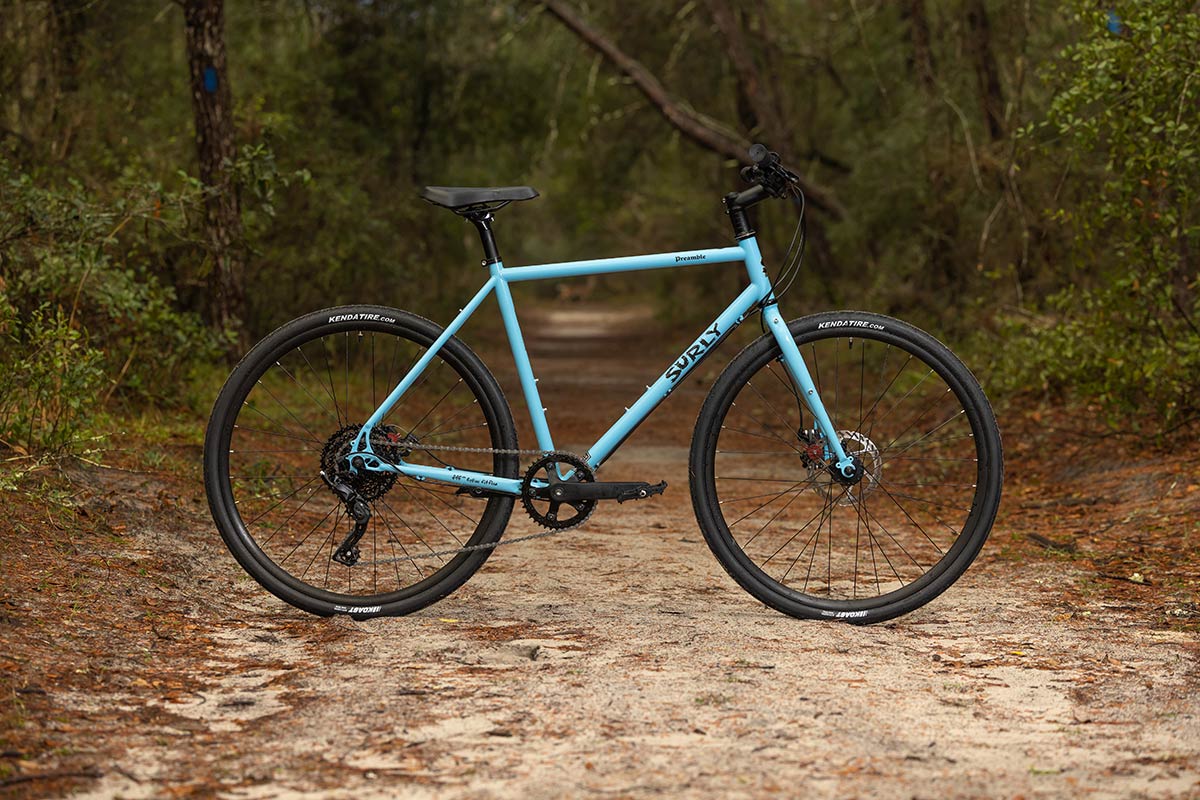 Preamble Flat Bar Skyrim Blue bike side view on gravel trail through woods