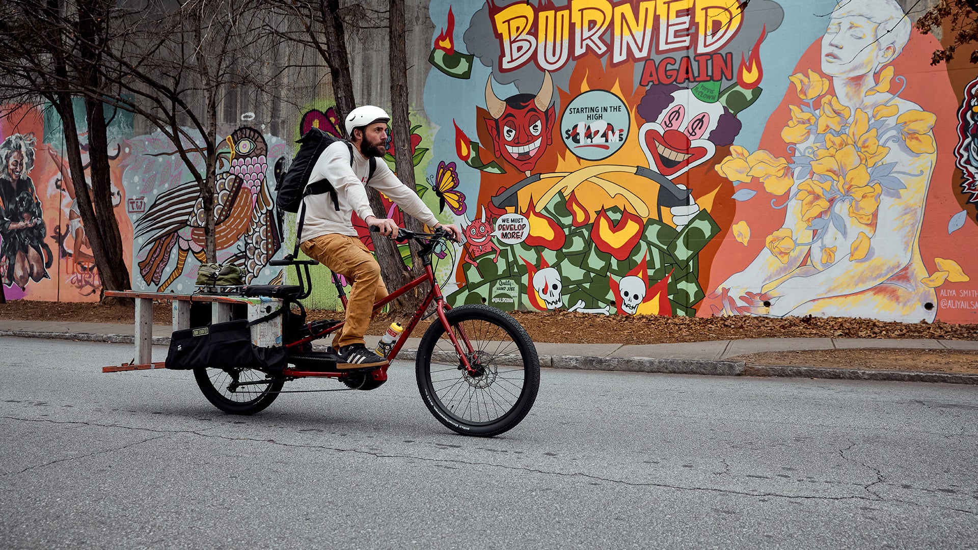 Person riding Surly Big Easy loaded with gear on street in front of mural