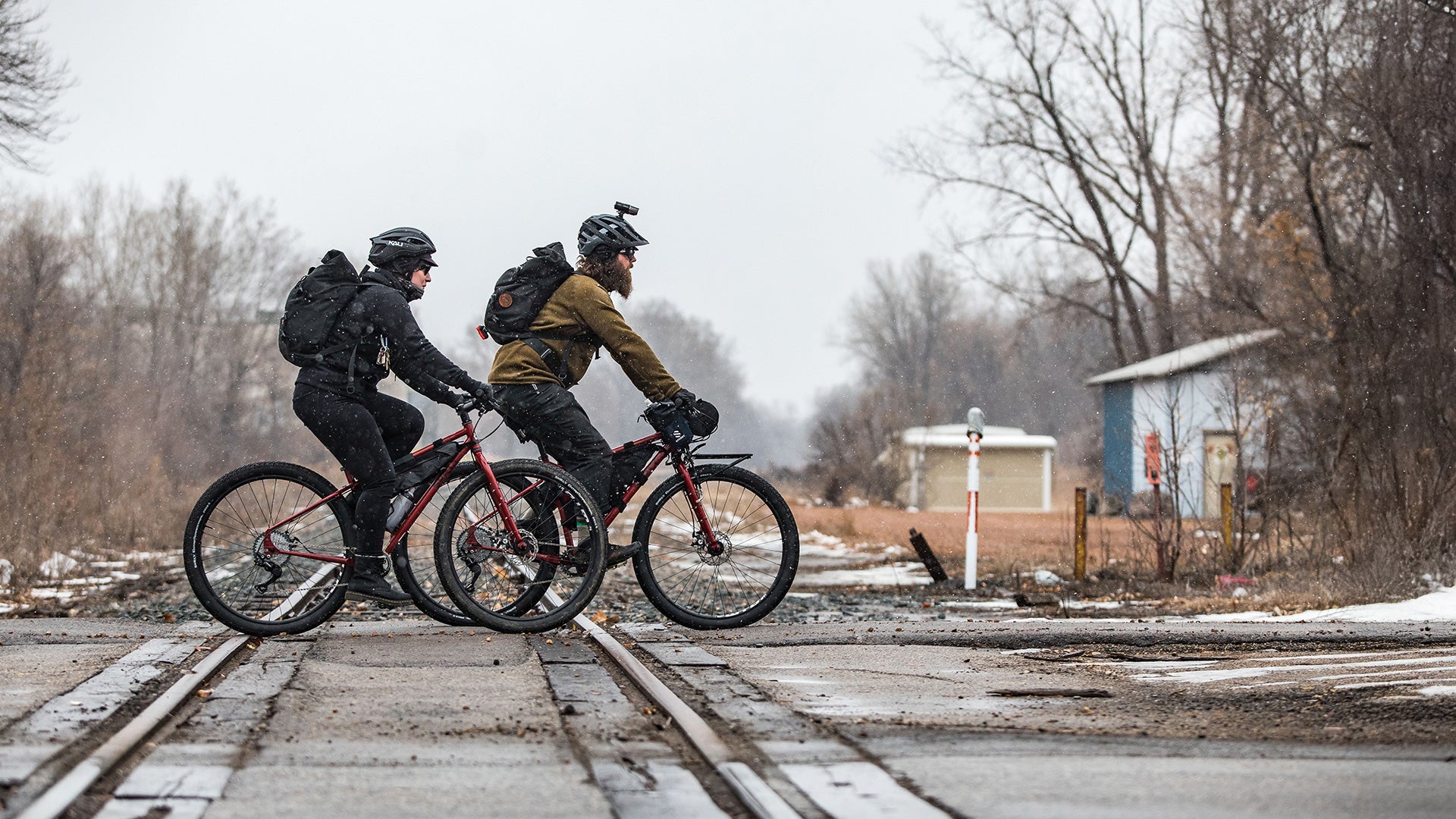 Two cyclists riding Surly Ogre bikes across rail road tracks