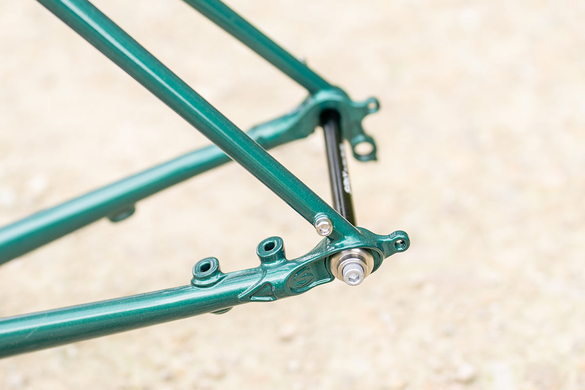 Surly Straggler Frameset in Subtropic Algae color detail view of rear dropout and thru-axle on gravel road