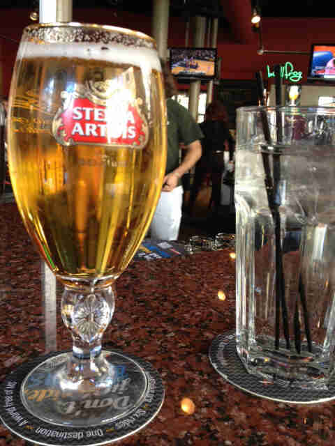 Close of view of a stemmed glass of beer, on a granite counter next to a glass of ice water, in a bar