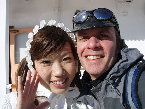 Front, headshot view of 2 people with their heads together, smiling for a photo