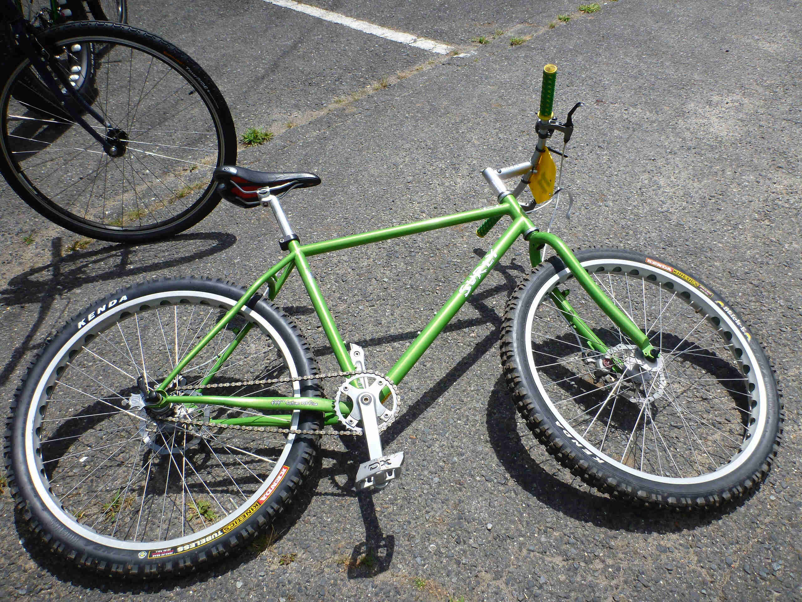 Downward, right side view of a green Surly 1x1 bike, laying on pavement
