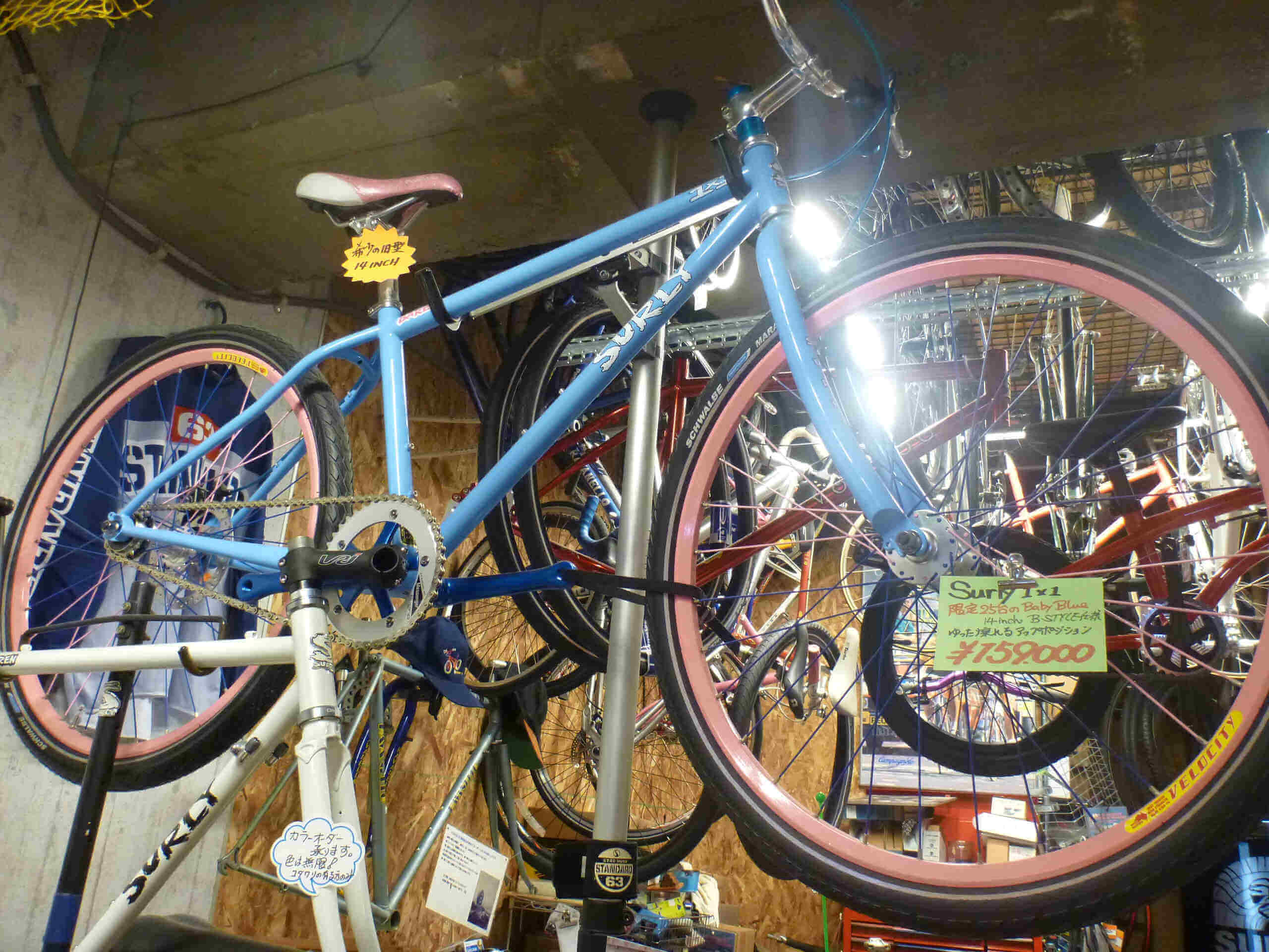 Upward, right side view of a light blue Surly 1x1 bike, hanging from a rack in a bike shop