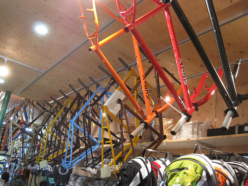 Upward view of a row of Surly bike frames, hanging a rack that's mounted near the ceiling in a bike shop