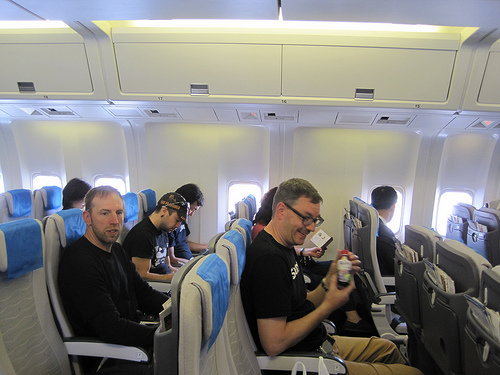 Side view of a people seating in seats, inside of a commercial jet