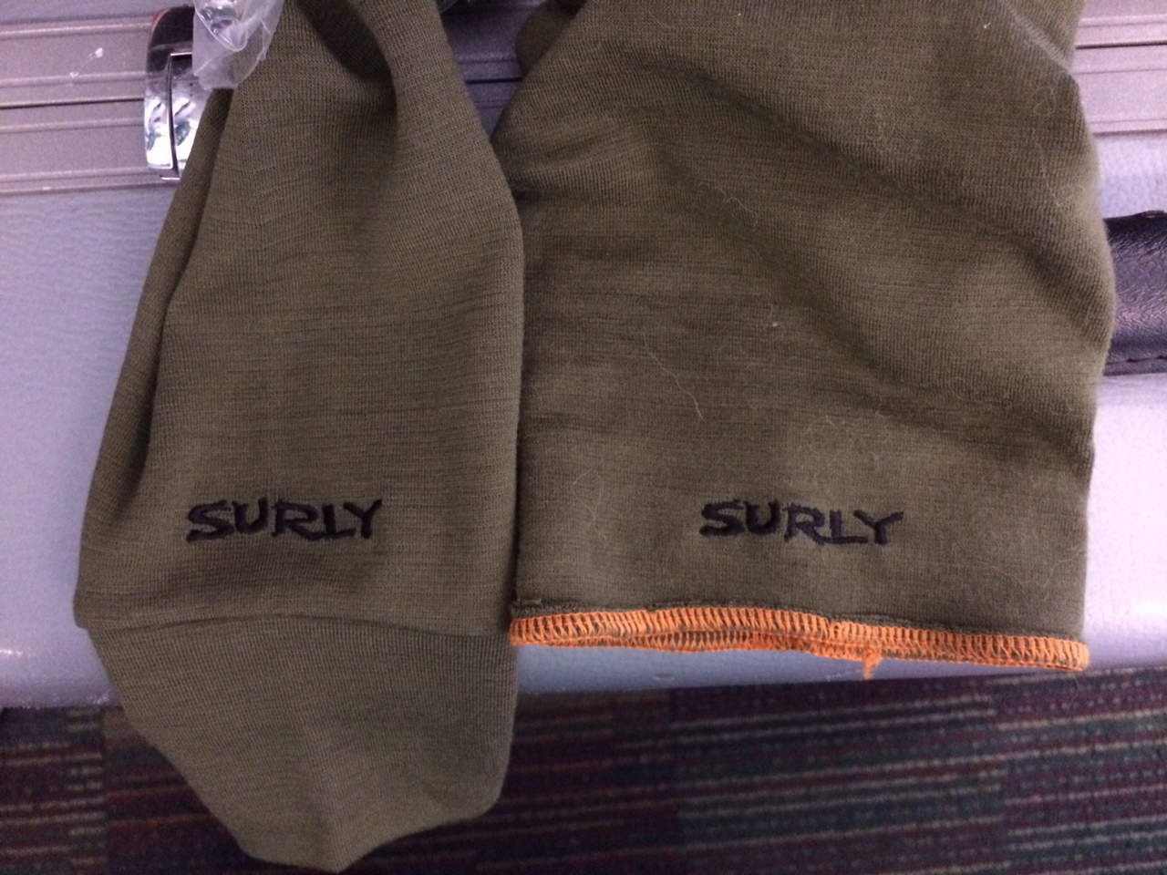 Downward view of 2 Surly long shirt sleeves, laying next to each other, one with tapered wrist cuff and one without