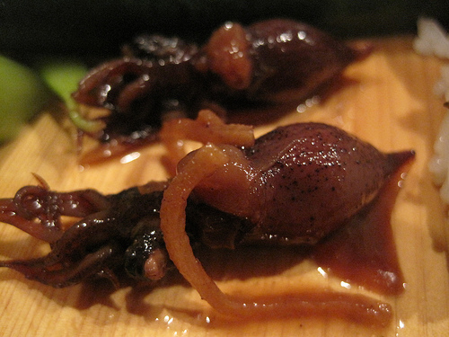 Close up view of 2 small squid on a bamboo platter