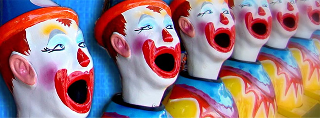 A row of plastic clown heads, side by side, with the mouths wide open