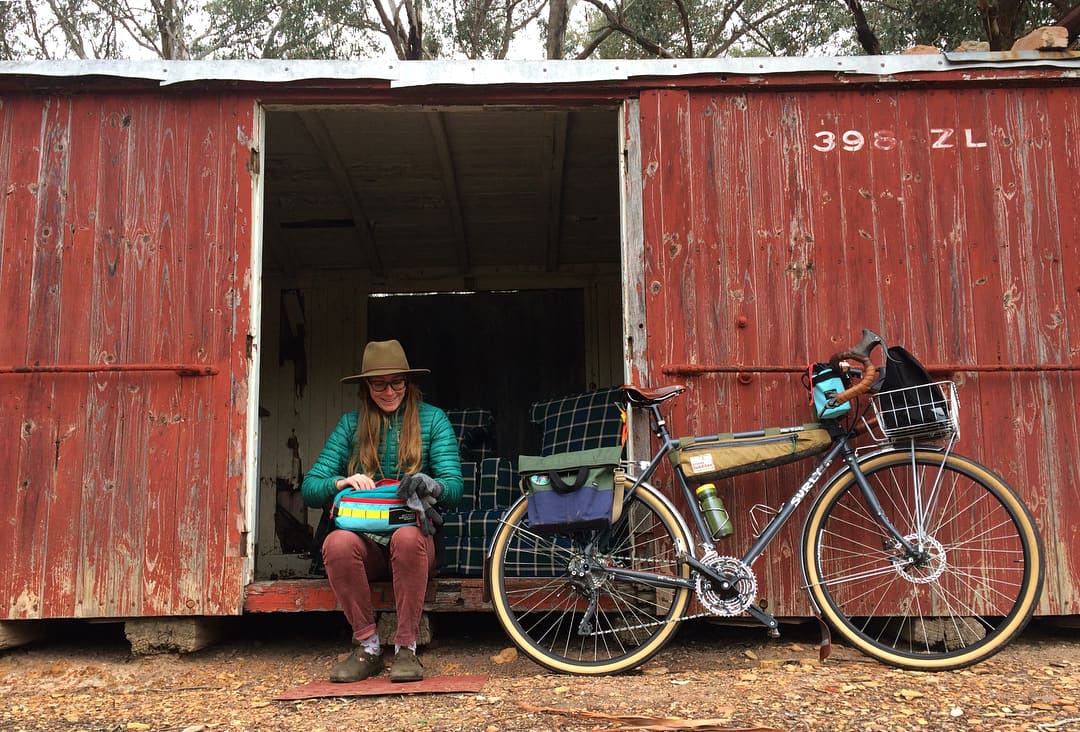 Pepper Cook sitting next to loaded Surly bike packing bike bag