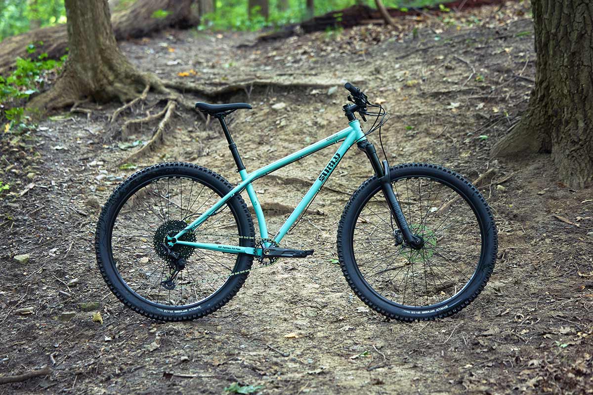 Surly Krampus front suspension bike in Blue Oyster Coat side view on rooty singletrack trail