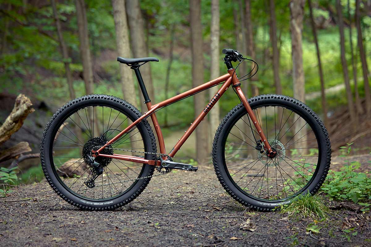 Surly Krampus rigid bike side view on forest trail in Chester Copperpot color
