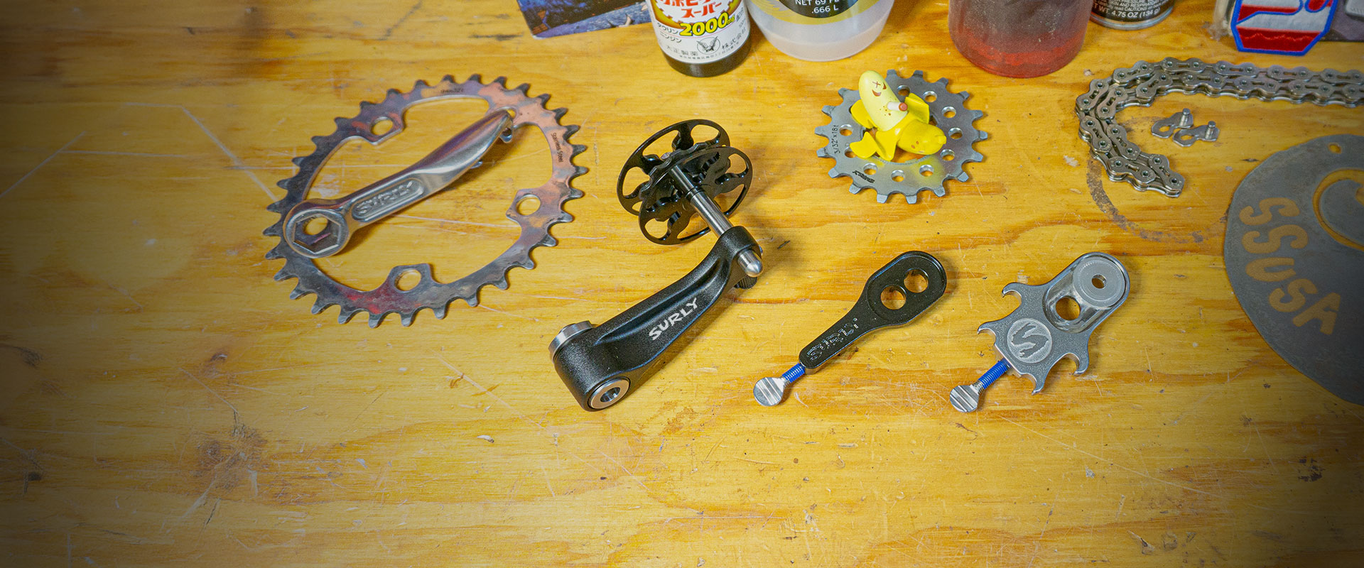 Surly Singleator, Hurdy Gurdy, and Tuggnut single speed parts on wooden work bench