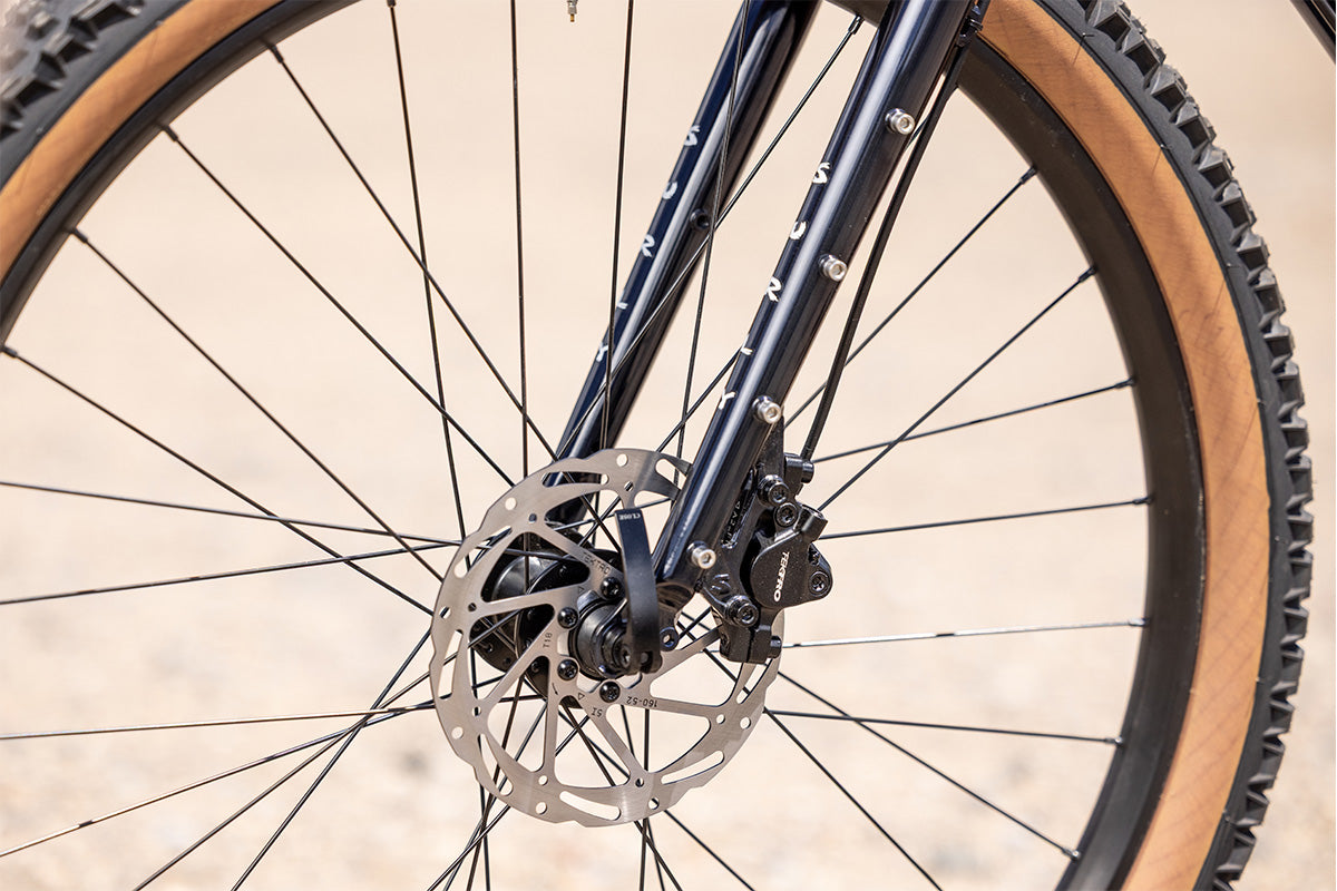 Surly Bridge Club bike outside focus on front wheel, fork, disc caliper and rotor with a blurred background