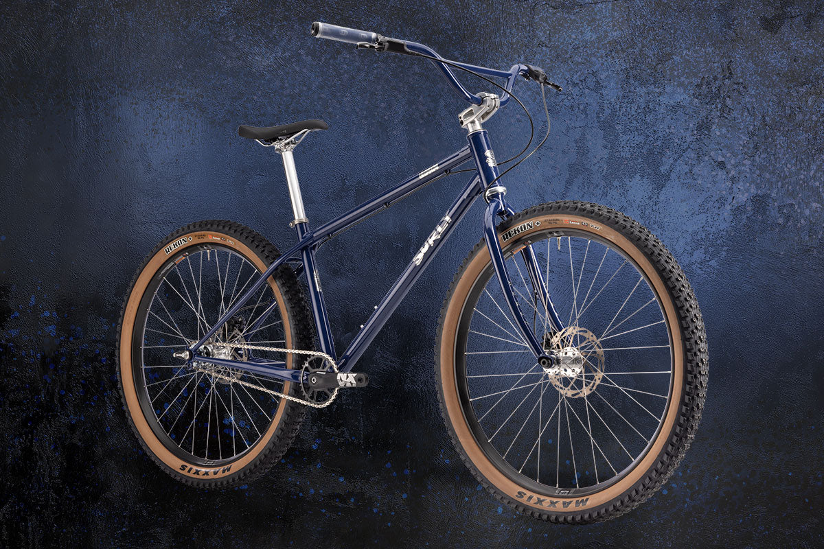 Blue bicycle with brown tires on a dark textured background