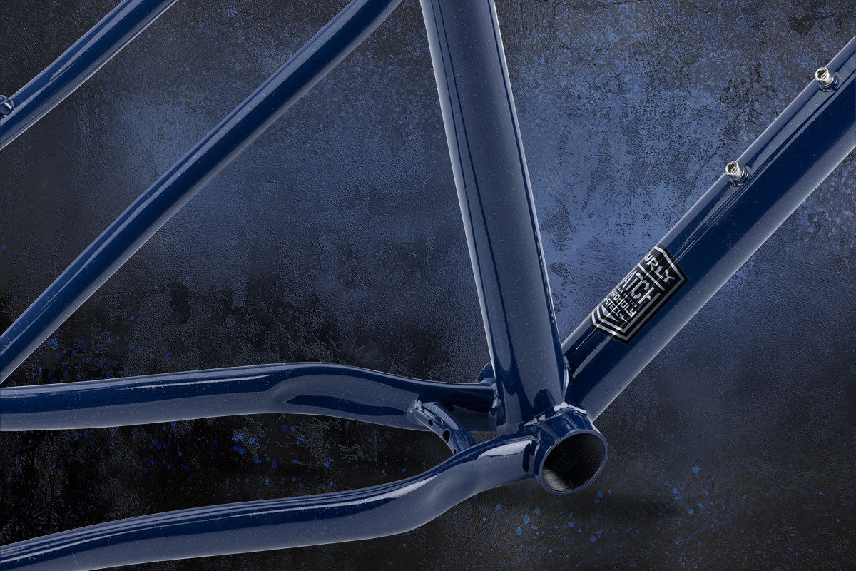 Close-up of a blue bicycle frame bottom bracket area with a dark textured background