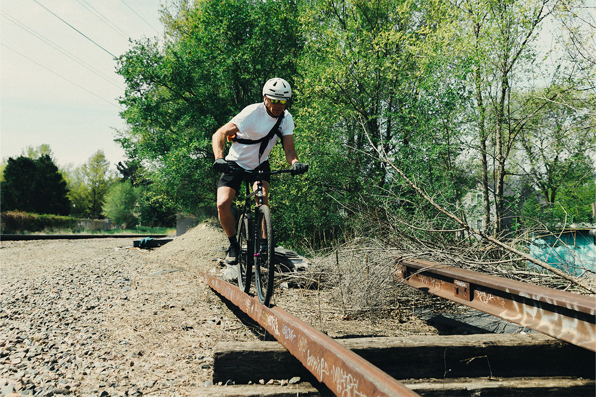 Person riding a bicycle on an old railway track with trees in the background