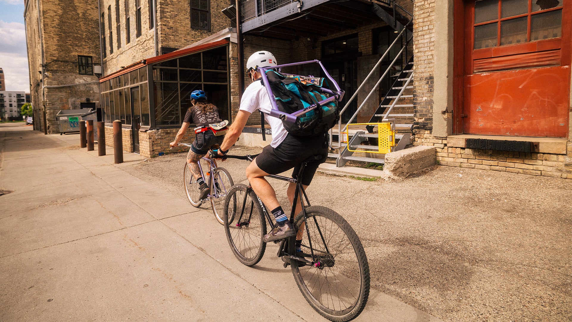 Two people riding bicycles on a city street with a building in the background