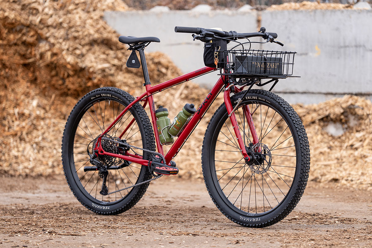 Red bicycle with a basket on a dirt path