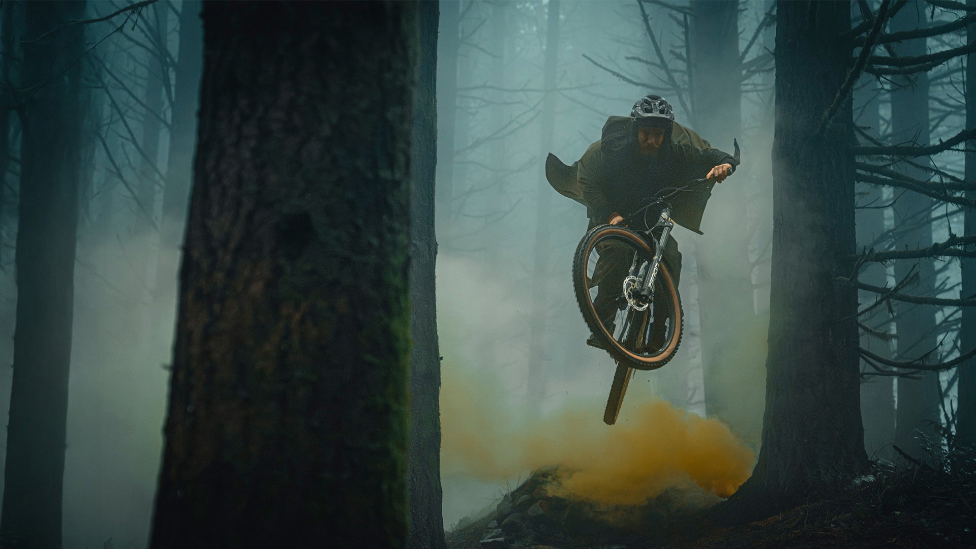 Person on a bicycle in mid-air amidst foggy forest