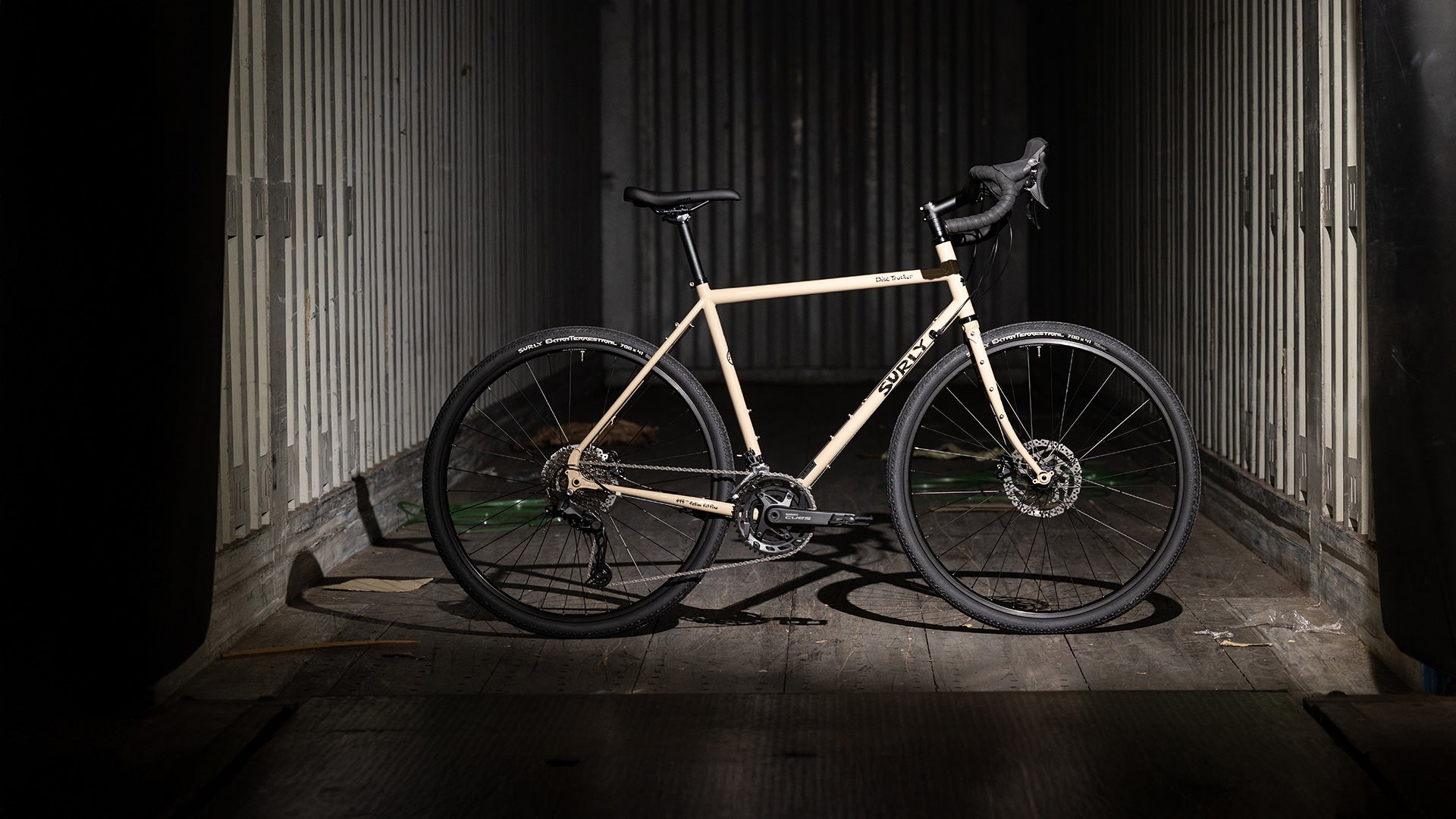 Surly Disc Trucker bike side view in tan color in side dark shipping container