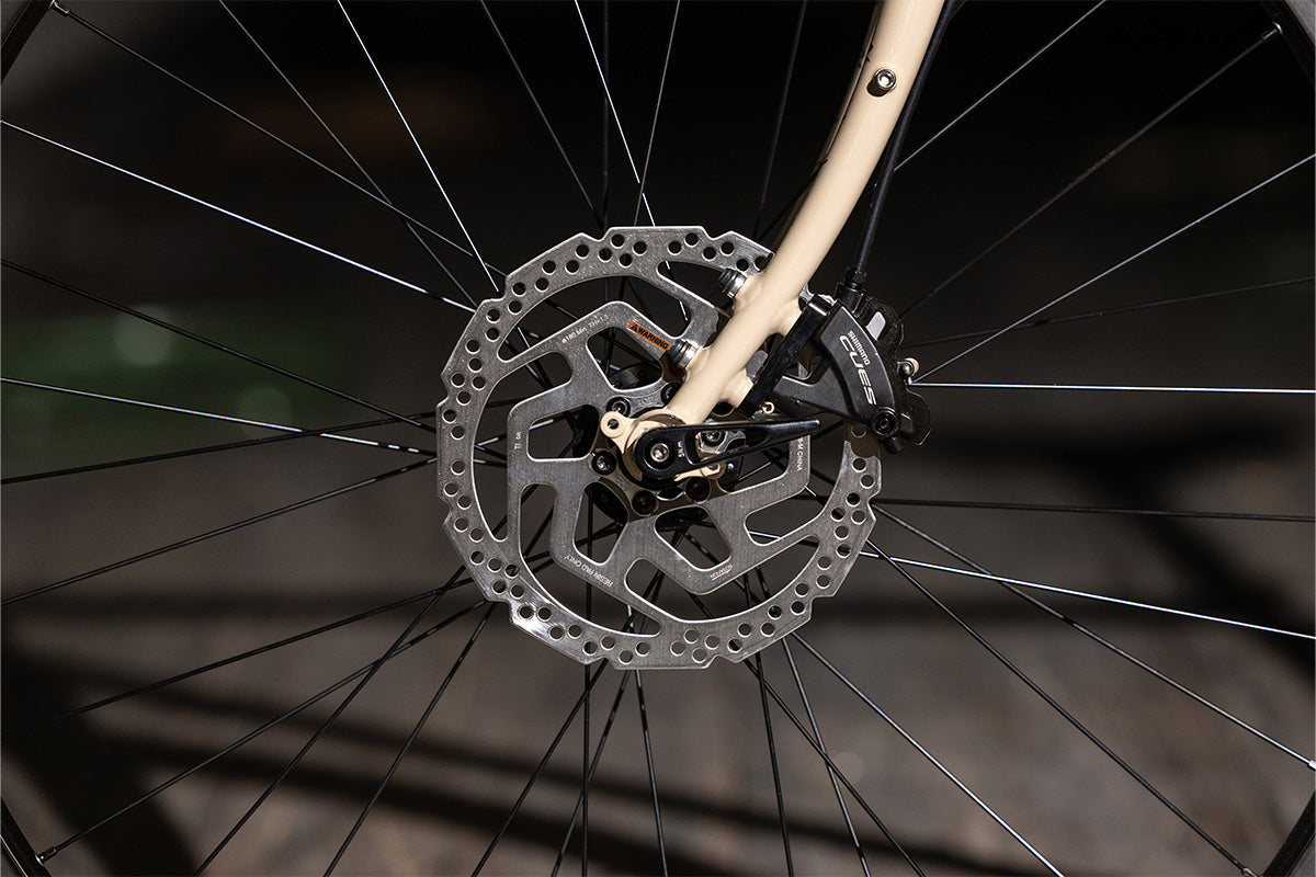 Surly Disc Trucker bike close-up of front disc and brake caliper on dark background