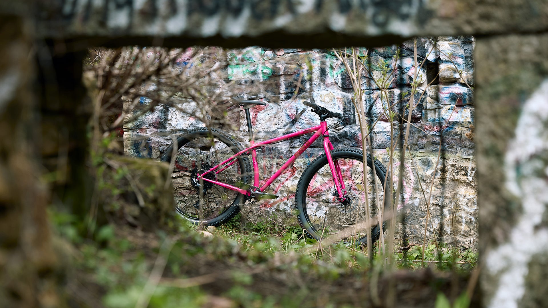 Surly Krampus Prickly Pear Rigid Bike outside leaning against brick wall with graffiti