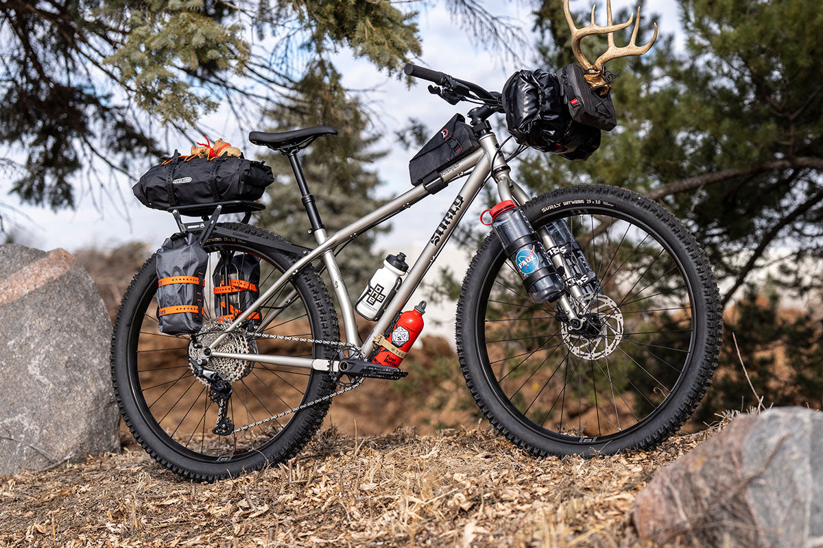 Bicycle with gear and supplies on a rocky trail with trees in the background