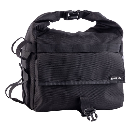 A black Surly waterproof pannier bag with a roll-top closure, front utility pocket, and adjustable shoulder strap, shown on a plain white background.
