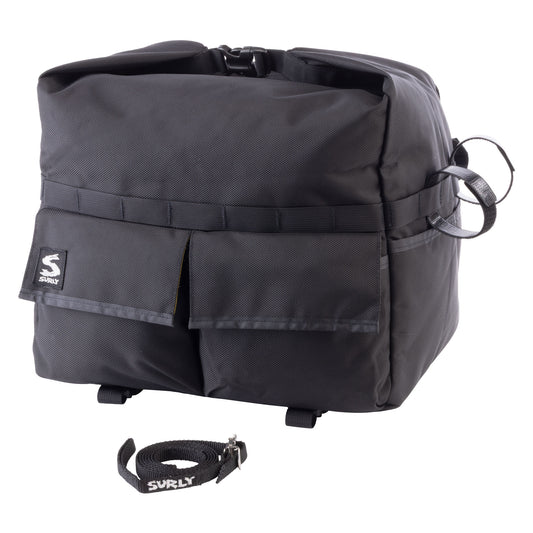 A black Surly bicycle pannier bag with a front utility pocket and a separate black carrying strap placed below it, shown on a plain white background.