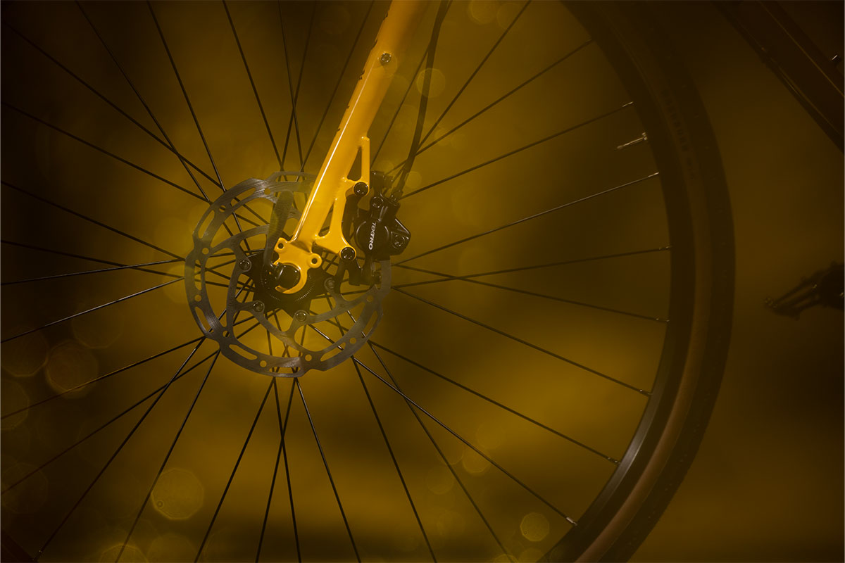 Close-up of a bicycle wheel with a yellow rim and hub on a dark background
