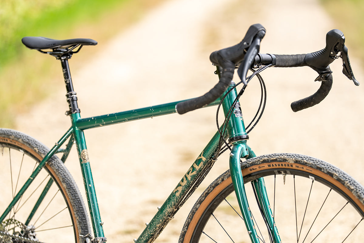 Surly Straggler bike in Subtropic Algae color three-quarter side view on gravel road in sun