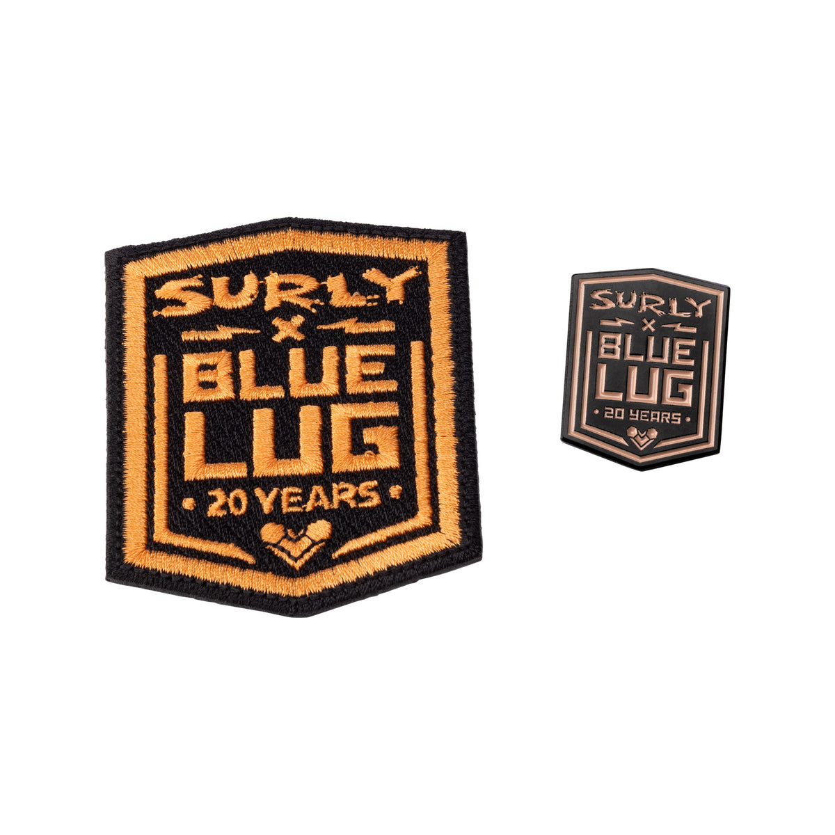 Two embroidered hexagonal patches on a plain white background. The larger patch reads 'SURLY x BLUE LUG 20 YEARS' in orange and black, and the smaller matching patch appears to the right.