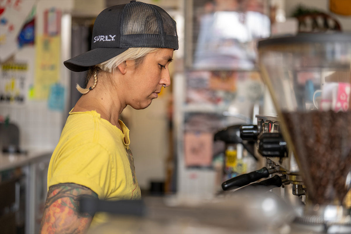Person wearing Surly hat while making coffee