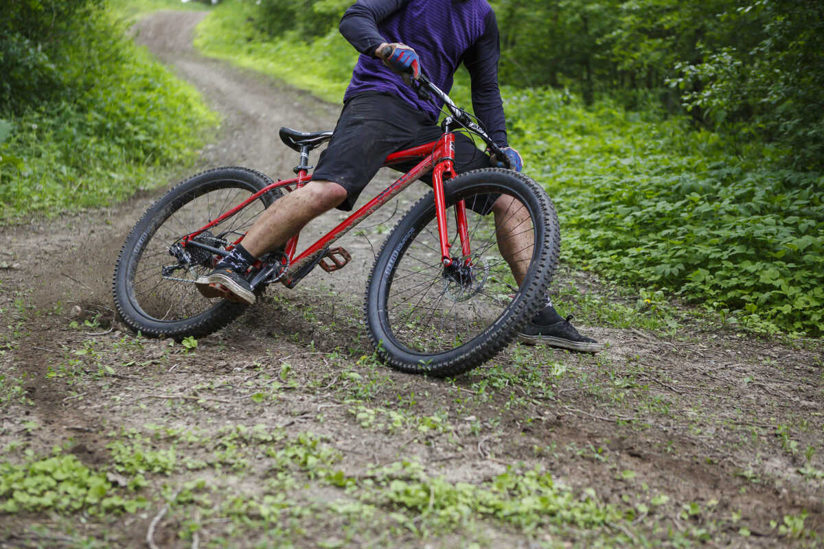 Mountain biker riding a Surly Krampus drifting on dirt corner with food out