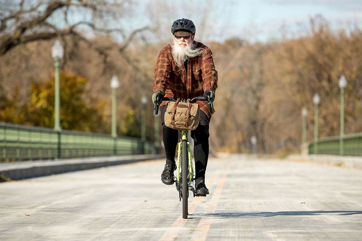 Person riding Disc Trucker across bridge wearing warm cycling apparel and flannel shirt with handlebar bag