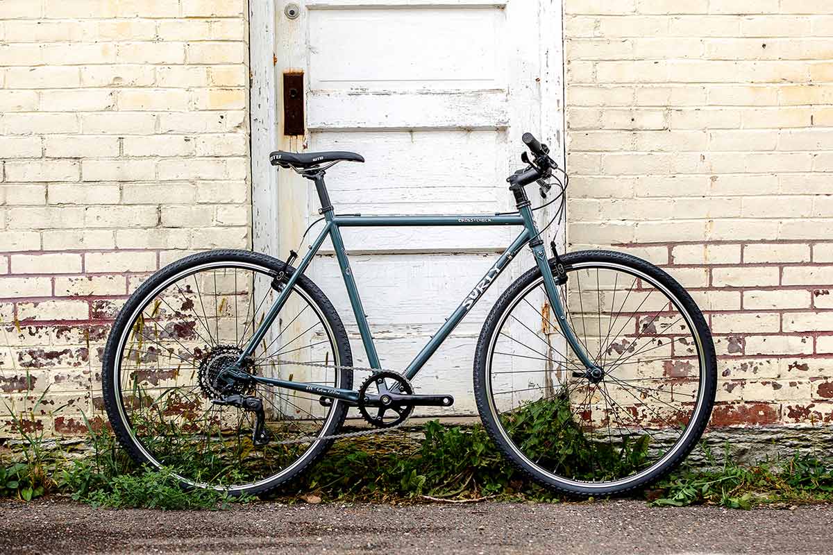 Cross-Check BlueGreenGray complete bike side view leaning against brick building