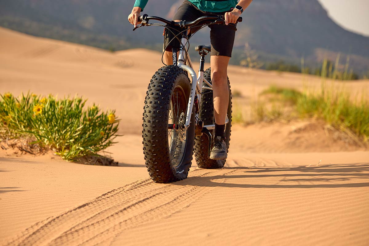 Person riding Surly Moonlander fat bike focus on tires in sand