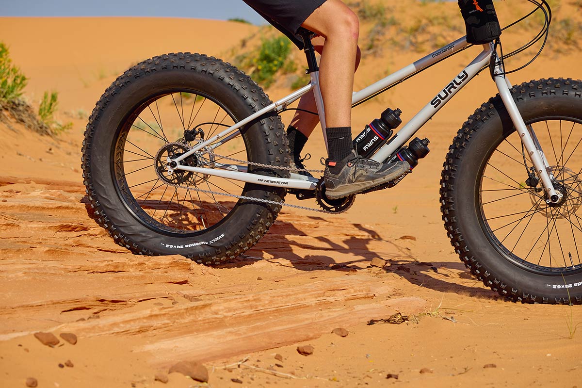 Person riding urly Moonlander fat bike down sandy and rocky steps focus on tires