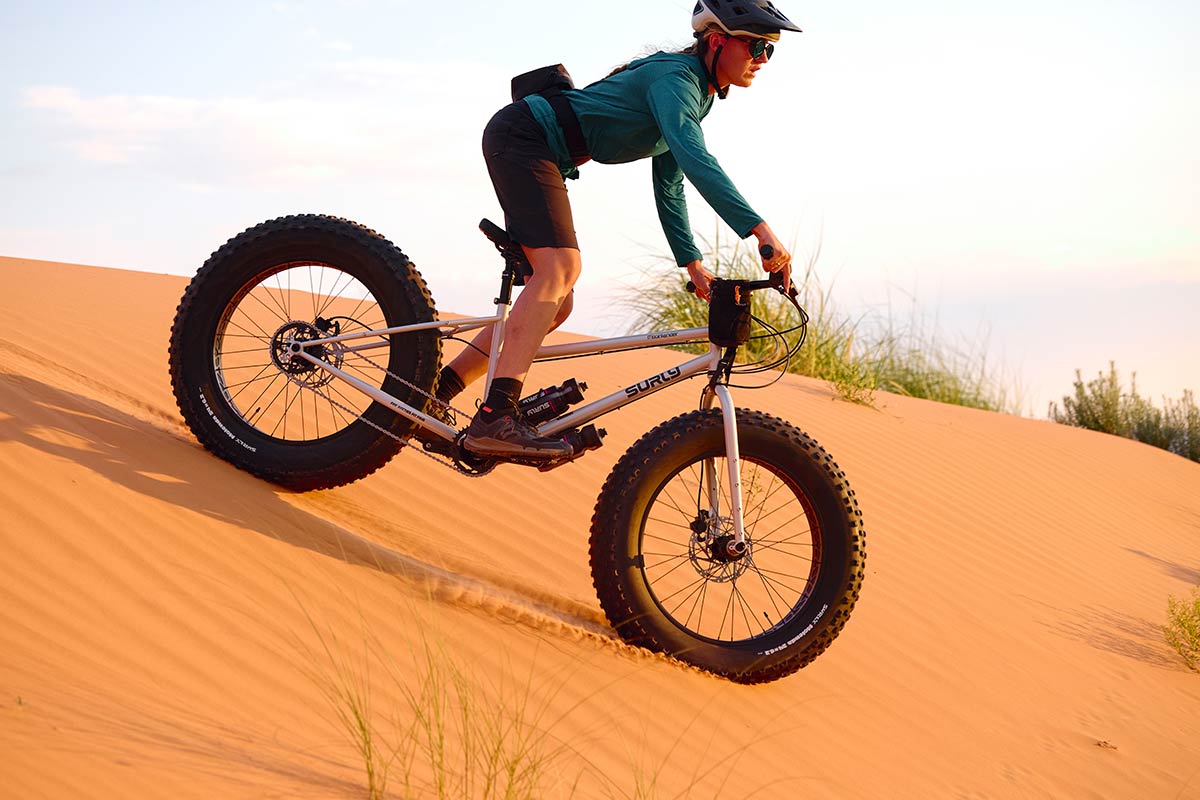 Person riding Surly Moonlander fat bike down sand dune