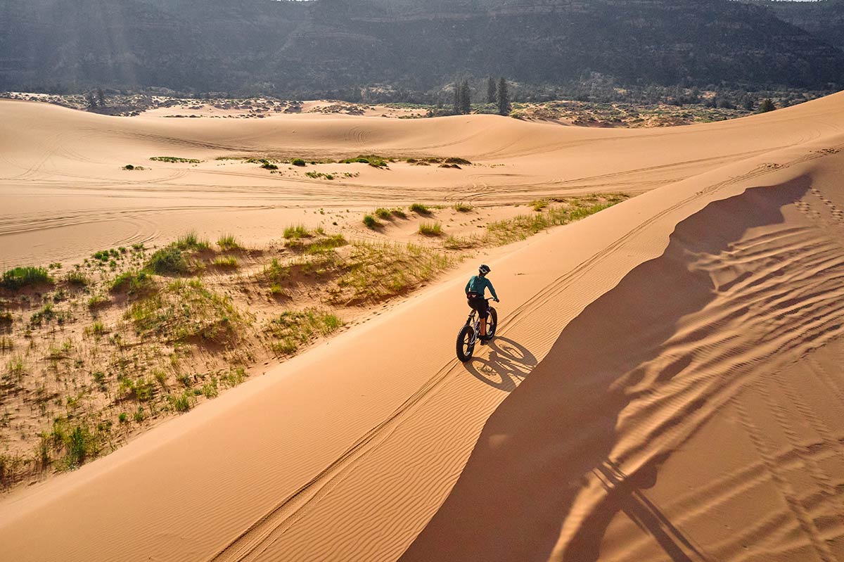 Person riding Surly Moonlander fat bike across sand dunes shot from above