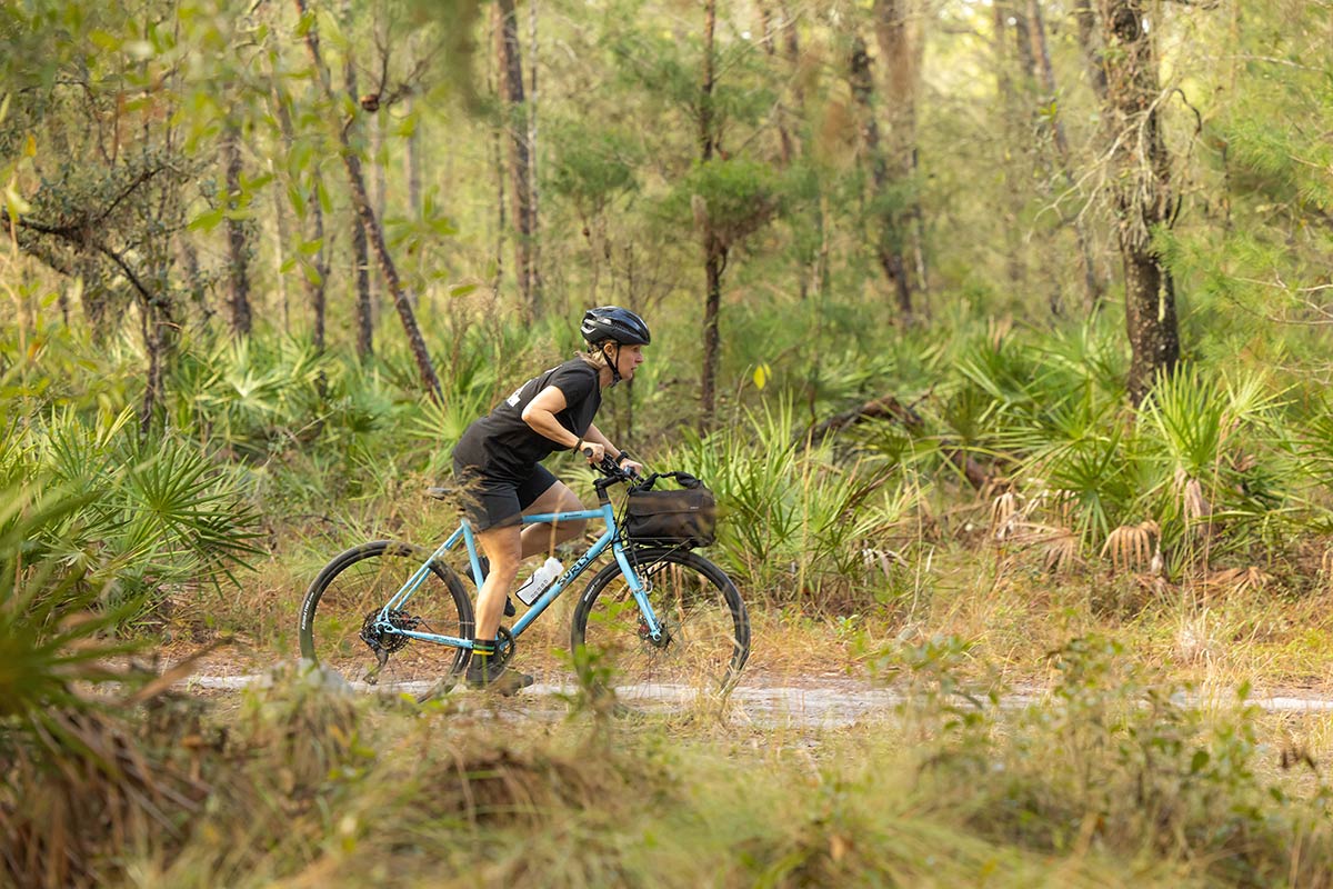 Person riding Preamble Drop Bar bike on gravel road through forest