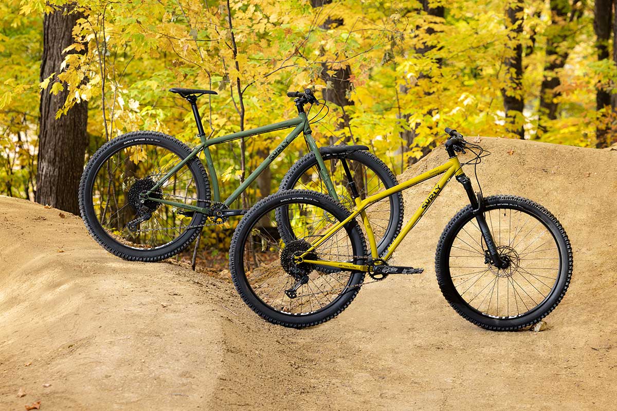 Surly Krampus rigid bike and front suspension bike together between freshly shaped berms in the woods