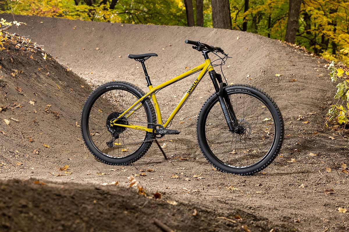 Surly Krampus front suspension bike next to freshly built berm trail in woods