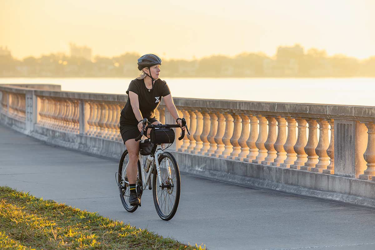 Person riding Surly Preamble Drop Bar Thorfrost White bike on bike path nest to river at sunset