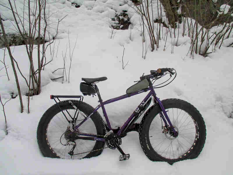 Right side view of a purple Surly fat bike, parked in deep snow