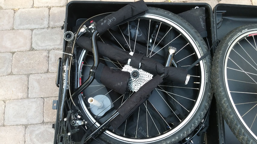 Downward view of the handlebar assembly of a Surly World Troller bike, packed on other parts, in a bike carrier case